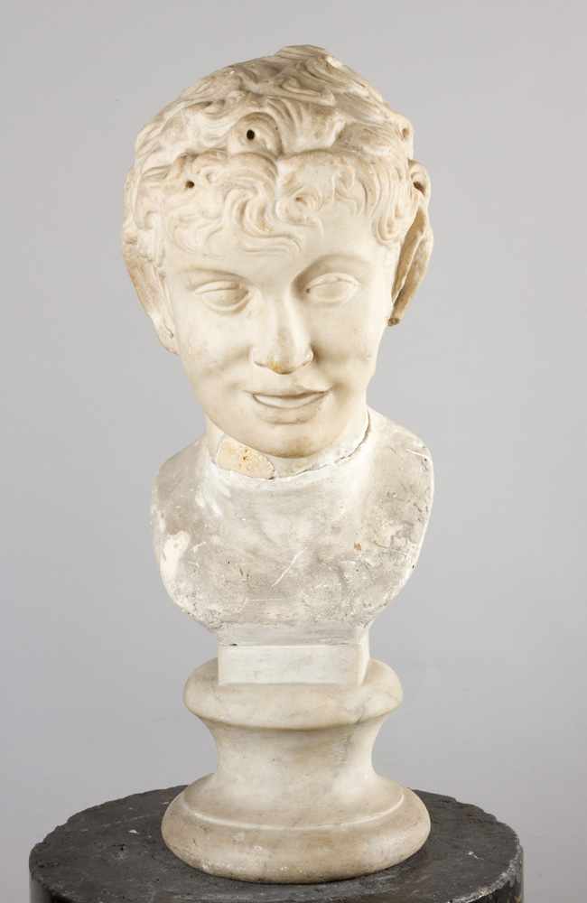 A Roman marble head of a young boy or satyr with curled hair, long pointed ears, deep eyes and