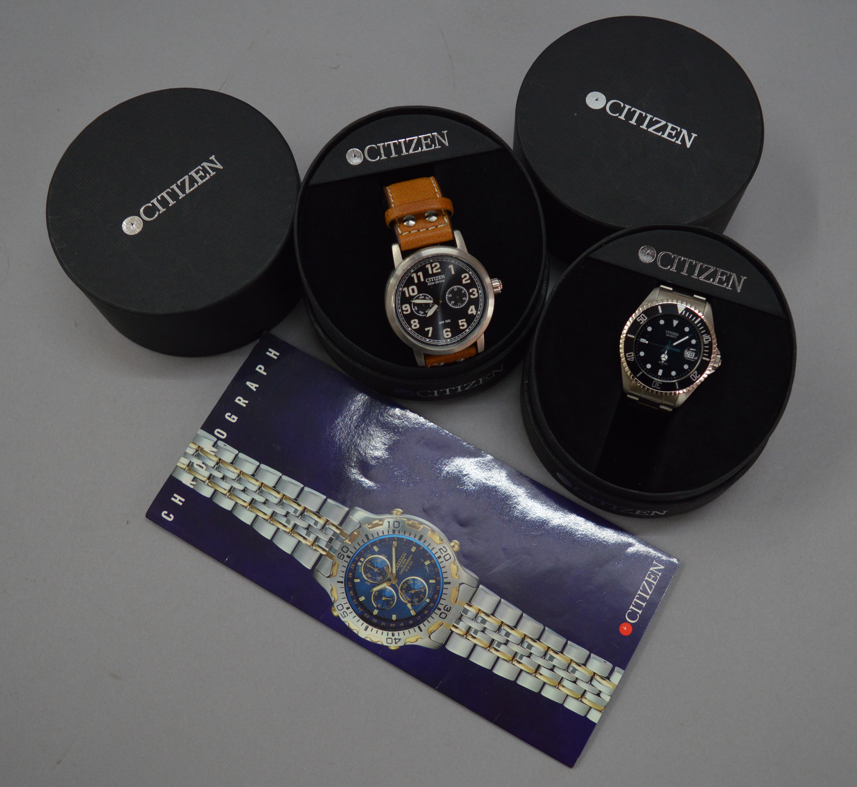 A Citizen Eco-Drive watch together with another Citizen example, both with boxes.