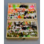 A large collection of fishing flies contained in a double sided wooden case