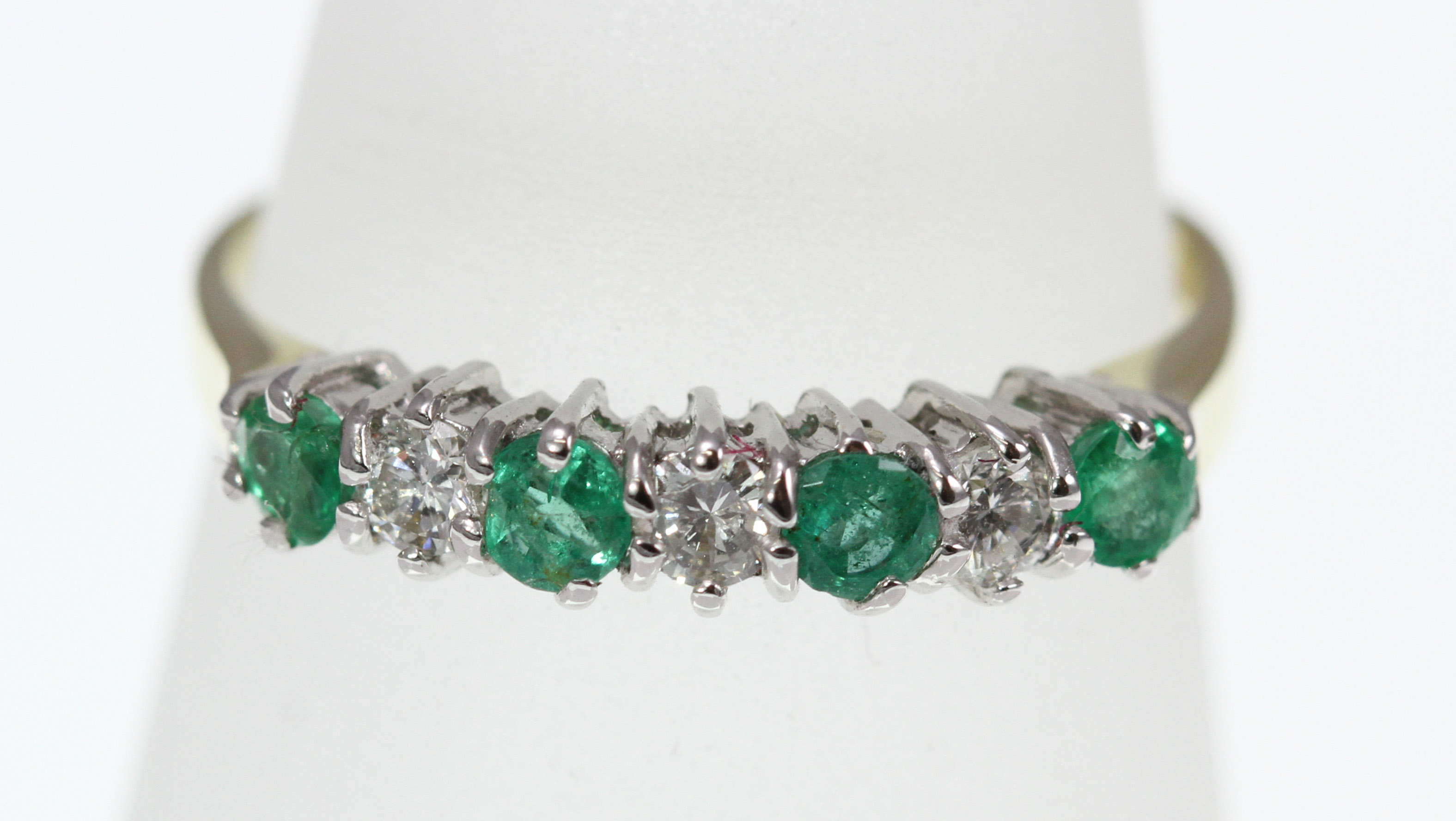 An 18ct H/M emerald and diamond 7 stone ring, approx total diamond weight 0.