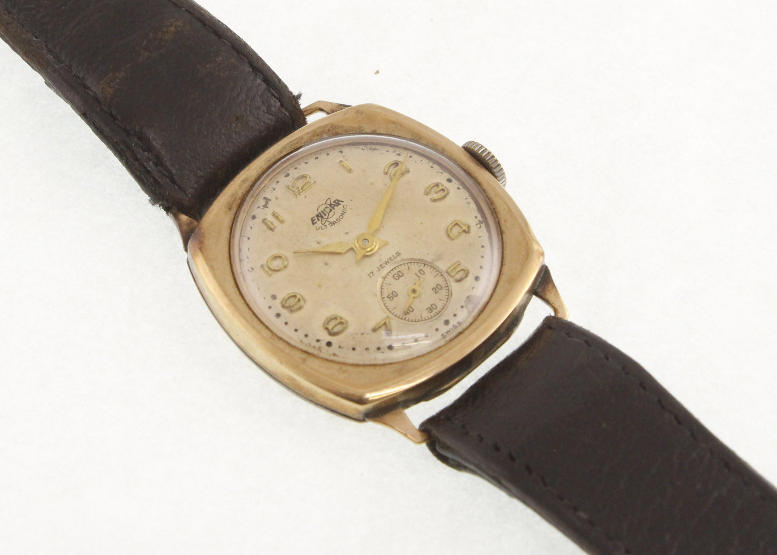A 1950's 9ct cushion-shaped ENICAR manual-wind wristwatch with fitted leather strap,