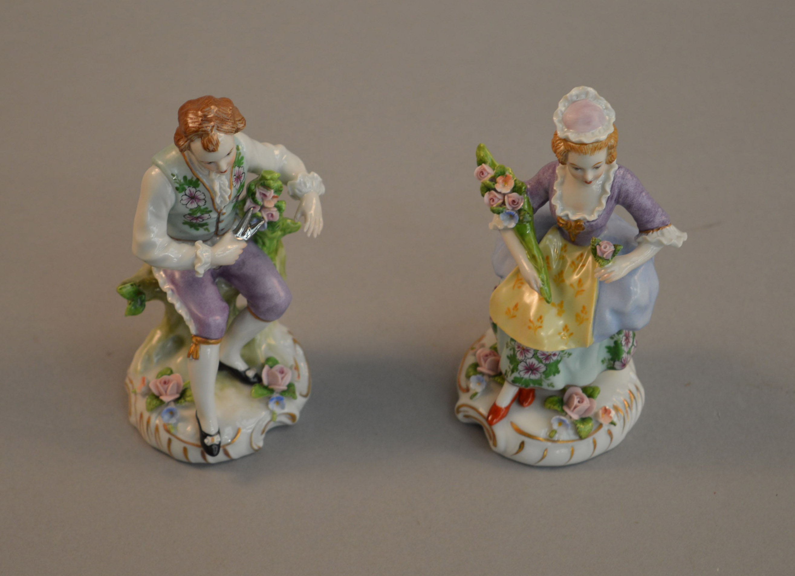 A pair of Sitzendorf Dresden flower figures of a seated man and woman. Woman 12.5cm tall.