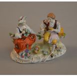 A Dresden Sitzendorf group figure of a seated man and woman on tree stumps. 13cm tall.