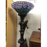 A modern ornate standard lamp decorated with dolphins leaping and a Tiffany style lampshade