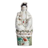 A Chinese polychrome decorated figure of a Guanyin with child, sitting on a lotus, about 1900, H