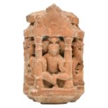 A dancing God holding a shell, sitting in a niche and flanked by two temple lions, pink sandstone,