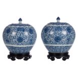 A pair of Chinese blue and white floral decorated ginger jars and covers, with symbols and fish,