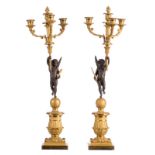 A pair of French patinated and ormolu bronze candelabras, the candlestick sections held bij