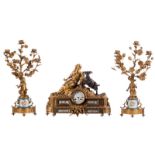 A Nap. III three-piece garniture in gilt bronze, the base of the candlesticks and the plaques of the