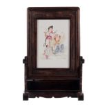 A Chinese wooden carved table screen with a famille rose porcelain plaque, decorated with an