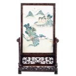 A Chinese tablescreen with a polychrome porcelain plaque, depicting a landscape, on a carved