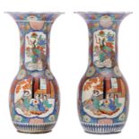 A pair of Japanese polychrome floral decorated vases, the roundels with an animated scene,