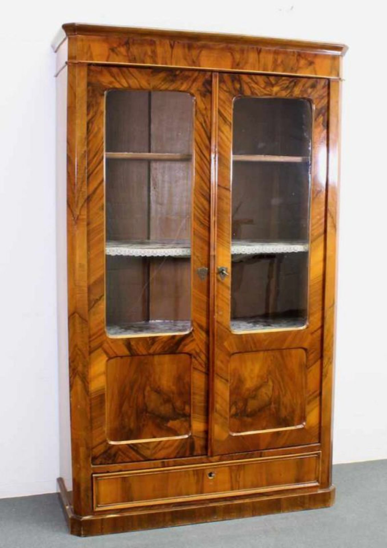 Vitrine, 2. Hälfte 19. Jh., Nussmaserholz, zwei teilverglaste Türen, im Sockel ein Schubfach, 174