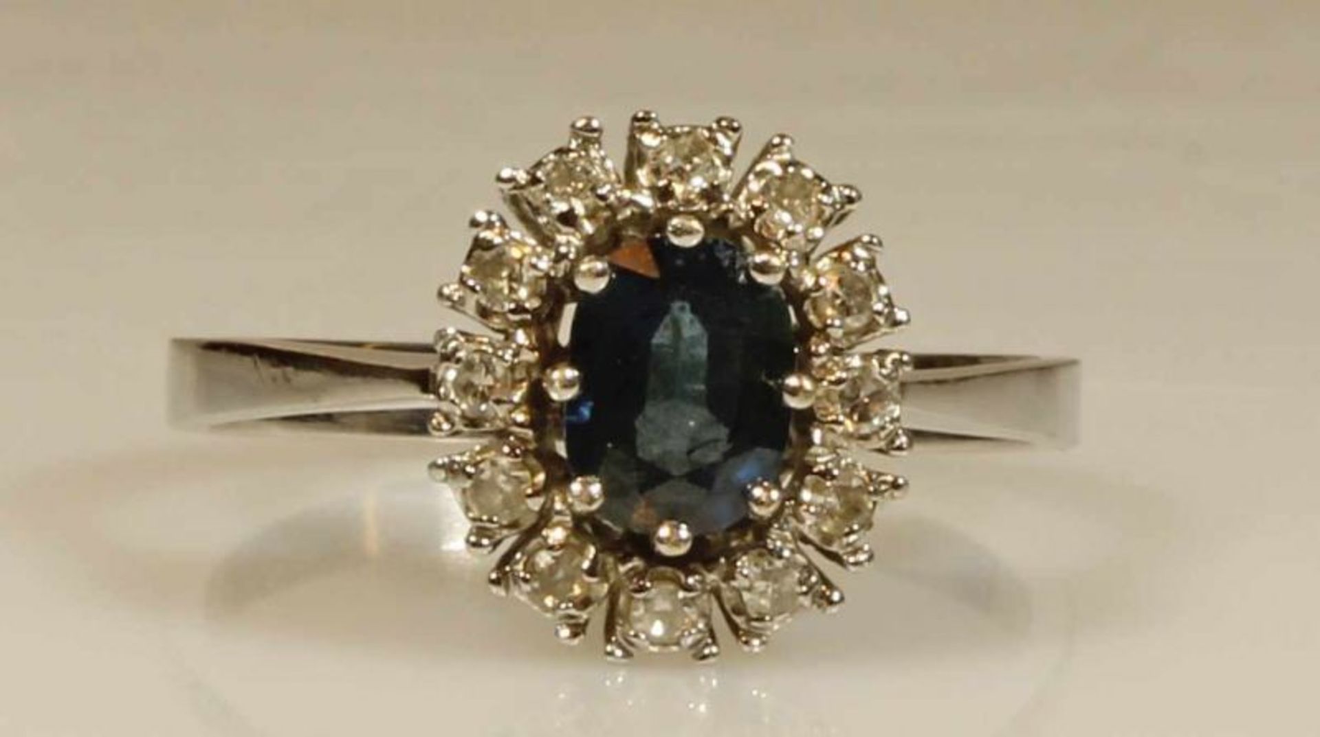 Ring, WG 585, 1 oval facettierter Saphir, 12 Besatz-Diamanten zus. ca. 0.18 ct., 3 g, RM 19.5 20.