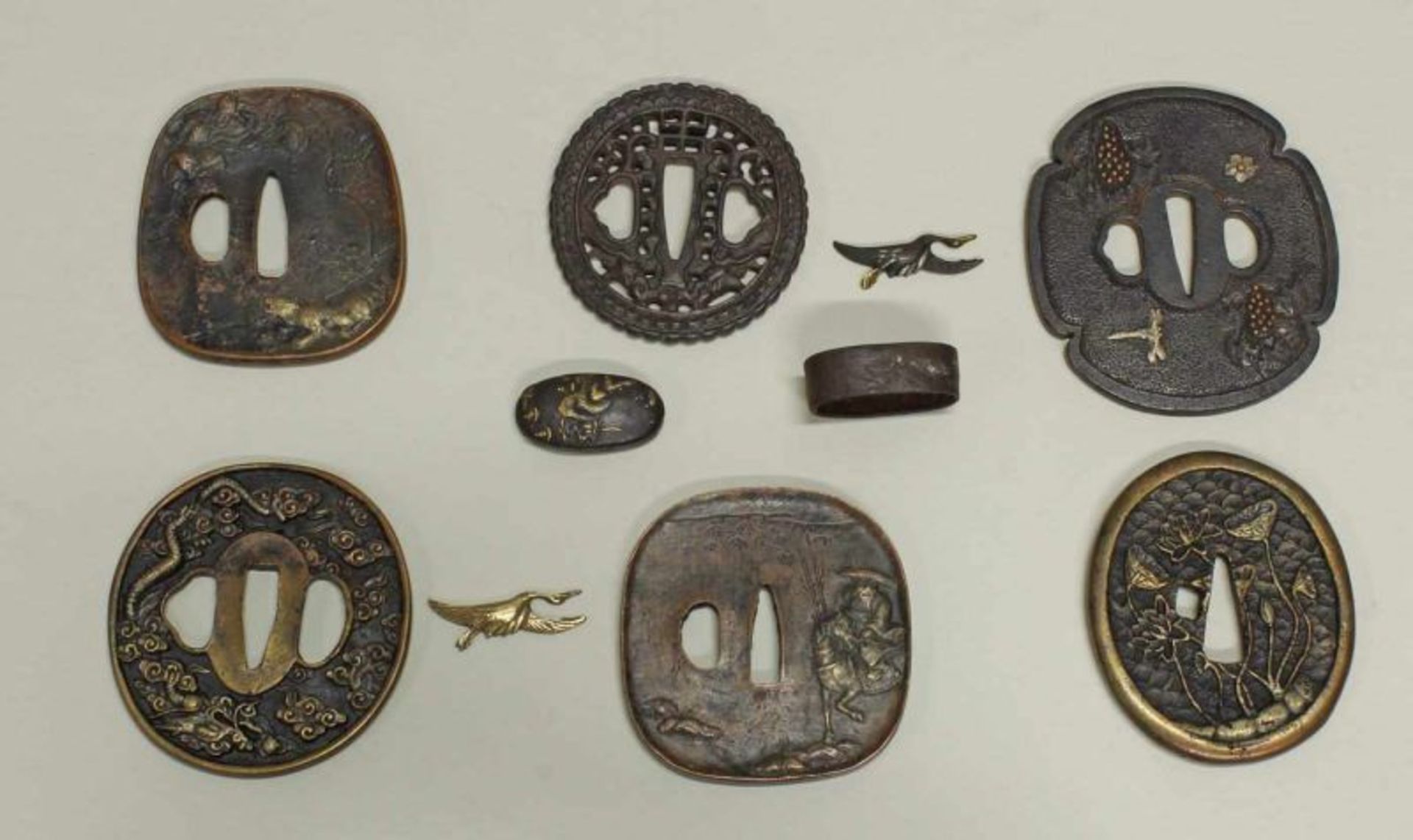 Konvolut von 6 Tsuba, 2 Menuki, Fuchi-Kashira, Japan, 19./20. Jh., Bronze, verschiedene Formen und
