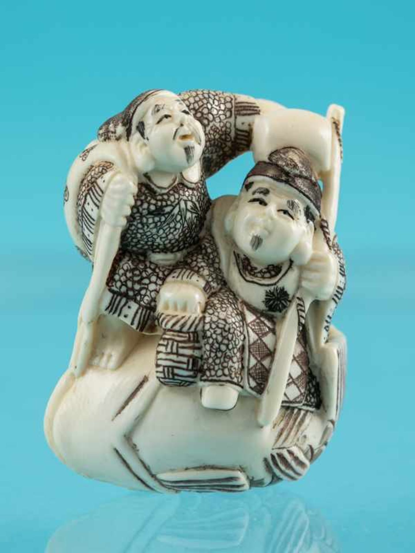 Netsuke, Anfang 20. Jh. Elfenbein. Schwarz - braun konturiert. Zwei männliche Figuren auf einem