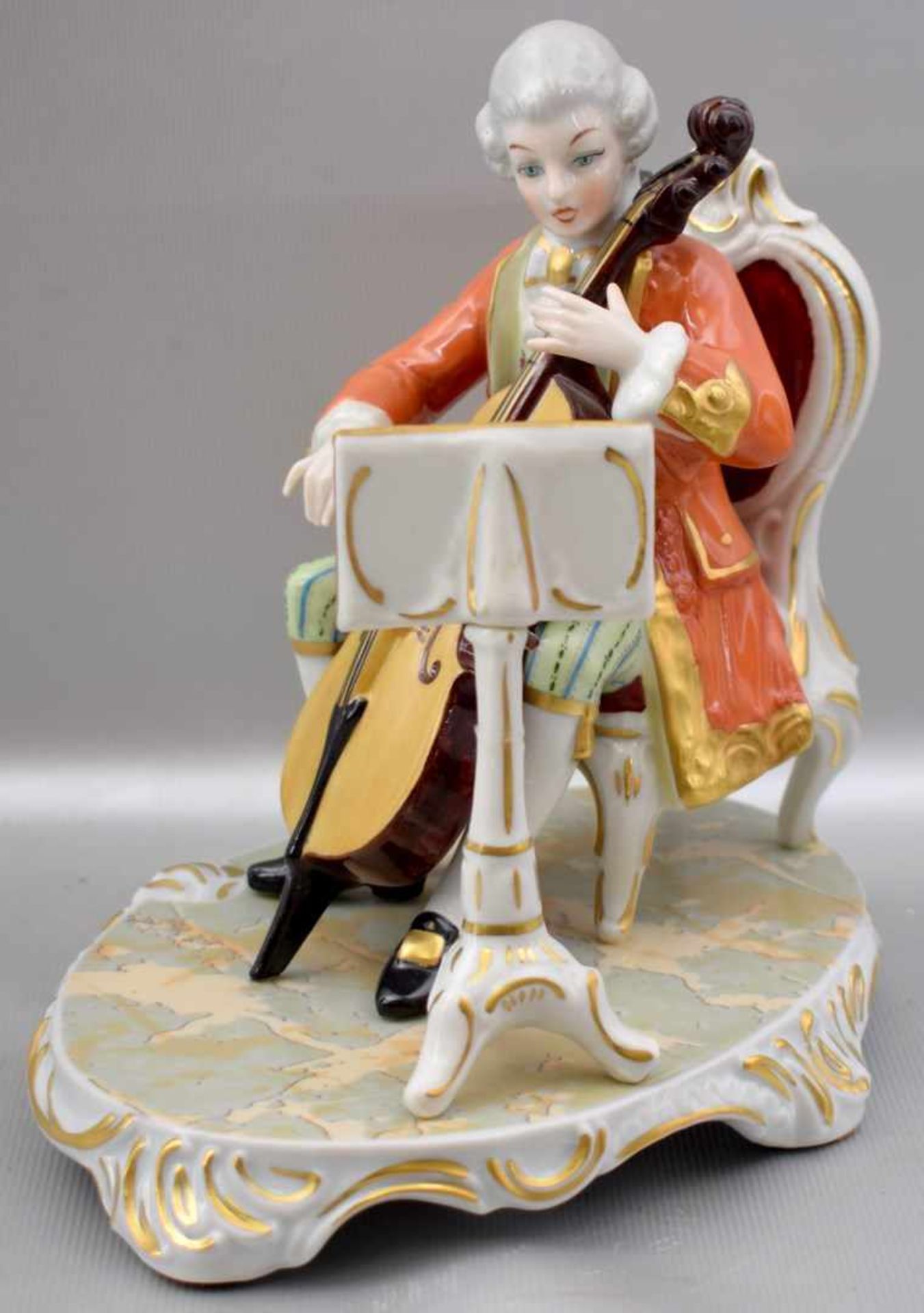 Cellospieler mit Notenblatt auf Rocaillensockel sitzend, im Barock-Stil, bunt bemalt, H 16 cm, FM