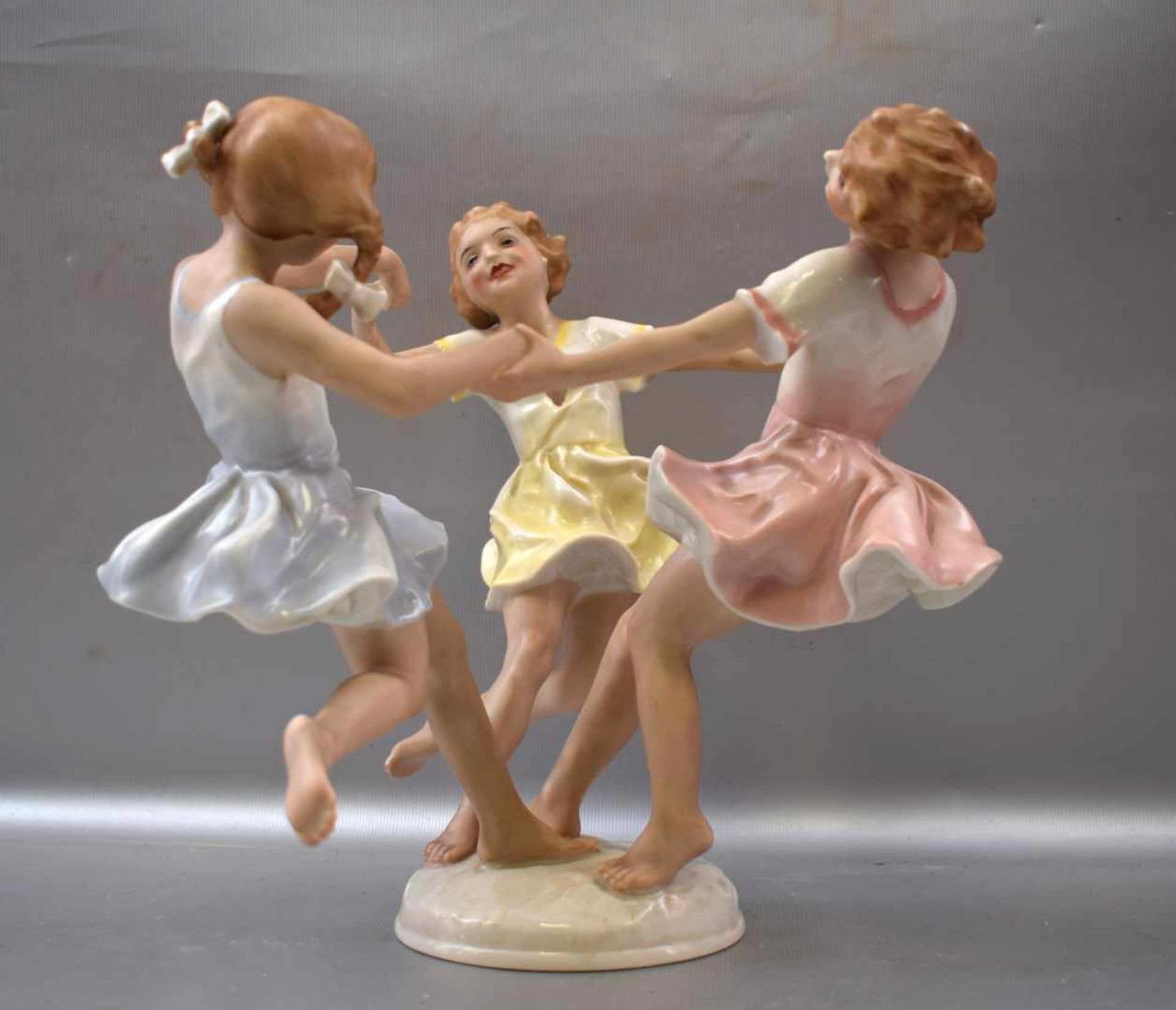 Kinderreigen drei tanzende Mädchen, auf rundem Sockel, bunt bemalt, im Sockel sign. K. Tutter, H