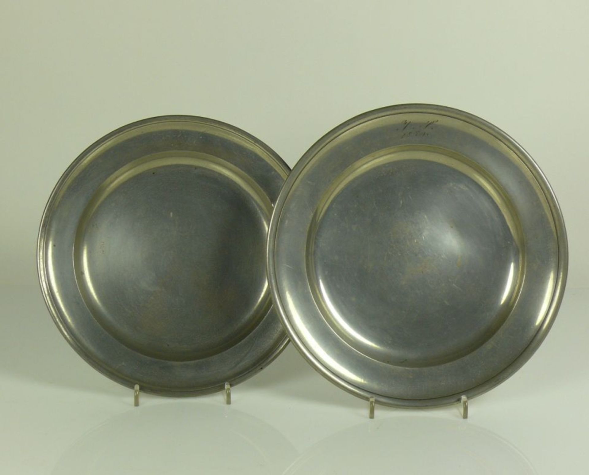 2 Teller (19.Jh.) Zinn; D: 24,5 bzw. 25,5 cm; glatter Spiegel; auf Fahne Monogr. JS und Datum 1859