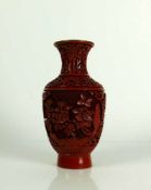 Rotlack-Vase (China) auf schwarzem, emailliertem Grund umlaufender Floraldekor im Relief; H: 17 cm