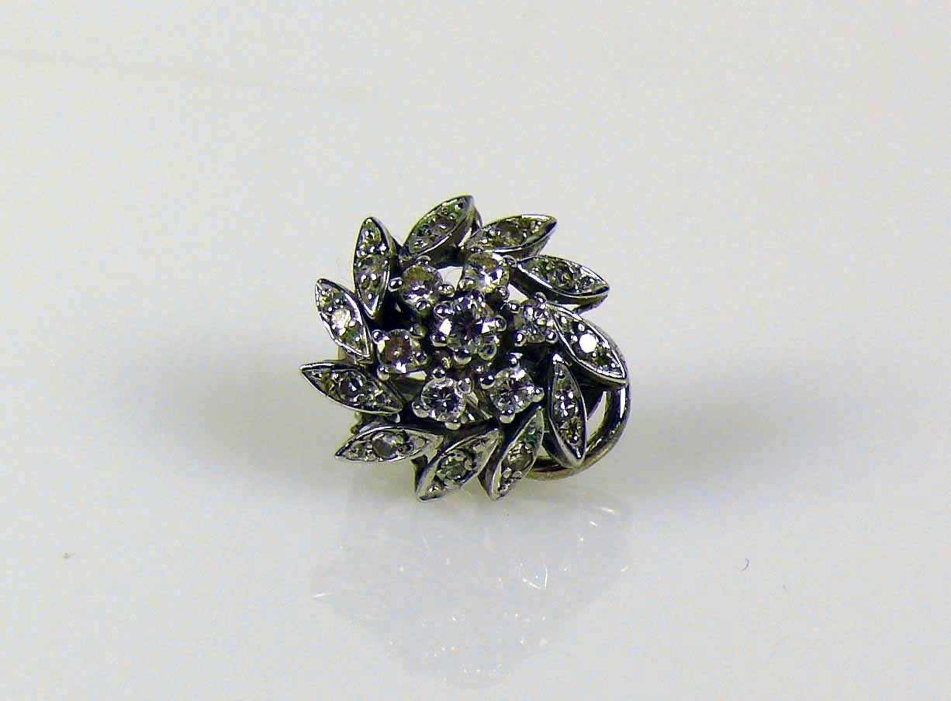 Ohrclip 14ct WG; blütenförmiger Dekor besetzt mit 7 Diamanten von zus. ca. 0,20ct; 3,5g