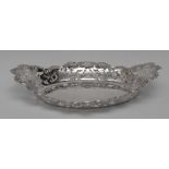 An Edwardian silver navette shaped cake dish, wavy border pierced and embossed with C-scrolls,