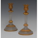 A pair of Empire style gilt metal mounted rock crystal candlesticks, fluted campana sconces,