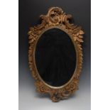 A 19th century Rococo giltwood oval mirror, carved with C-scrolls and flowers, 73cm high, 44cm wide,