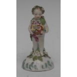 A Derby Patch Mark figure, of a cherub, wearing a leafy chaplet, holding a basket of flowers,