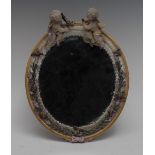 A Sitzendorf easel looking glass, the oval frame surmounted by cherubs and encrusted with flowers,