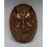 A 19th century giltwood boss, as a demon, carved in relief looking sideways, horns, oval shield, 25.
