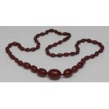 A single strand cherry amber graduated bead necklace, beads ranging from 12mm to 27mm long,