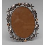 An Arts and Crafts gold mounted silver oval easel photograph frame,