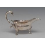A George III silver sauce boat, acanthus capped flying scroll handle, wavy border, hoof feet,