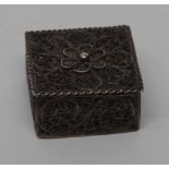 A 19th century silver filigree square patch box, typically worked with scrolls and flowerhead,