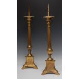 A pair of large brass altar pricket candlesticks, compressed campana drip-pans, reeded columns,