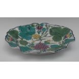 A Bow shaped oval dish, in relief with grapes, vine and flowers, decorated in tones of blue, green,