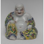 A Chinese porcelain and polychrome model, of Buddha, seated cross-legged, smiling,