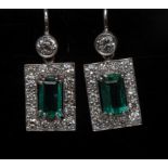 A pair of emerald and diamond drop earrings, each with a central baguette cut emerald, approx 0.