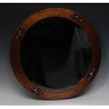 An Art and Crafts copper circular mirror, applied with four ovals, each with lozenges in relief,