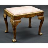 A Queen Anne style walnut foot stool, stuffed oval top, shells to knees, cabriole legs, pad feet, c.