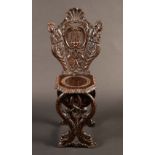 A 19th century Italian sgabello chair, carved with a heraldic device, terminal figures and dolphins,