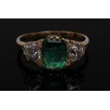 An emerald and diamond trilogy ring, central cushion cut Columbian emerald, 1.