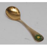 Georg Jensen - a silver-gilt and enamel spoon, decorated with a flowerhead, 15cm long, c.