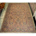 A handwoven middle eastern rug, floral designs in indigo, taupe and grey on a red ground.