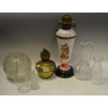 A Victorian over painted glass oil lamp; oil lamp chimneys; a frosted glass oil lamp shade;
