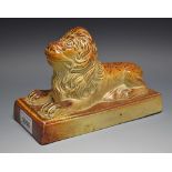 A Brampton brown salt glazed stoneware model of a recumbent lion, rectangular base, 19cm wide,