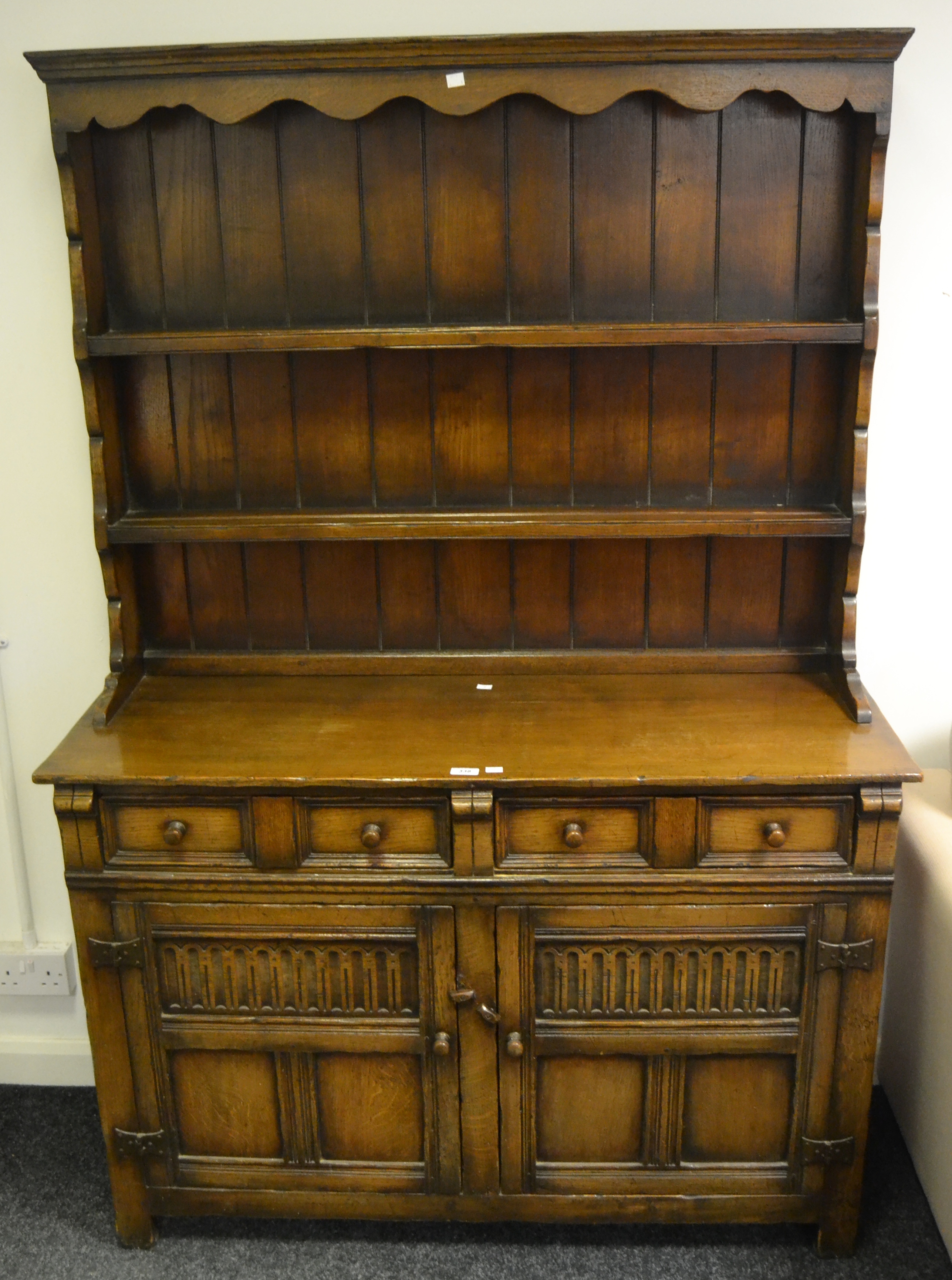 An Old Charm style oak dresser, shaped to frieze, two shelves above projecting base,