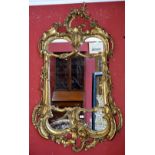 A gilt Rococo shaped mirror, foliate pediment, swags and foliage to frame.