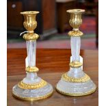 A pair of Empire style gilt metal mounted rock crystal candlesticks, fluted campana sconces,